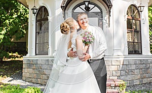 Wedding couple hugging, bride holding a bouquet of flowers, the groom embracing her