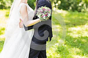 Wedding couple hugging, bride holding a bouquet of flowers, the groom embracing her