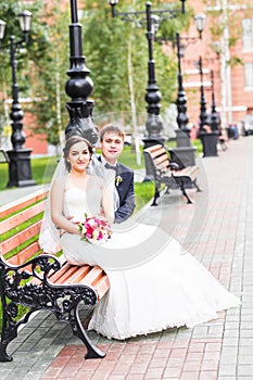 Wedding couple hugging, the bride holding a bouquet of flowers, groom embracing her outdoors