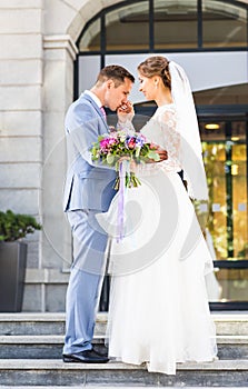Wedding couple hugging, the bride holding a bouquet of flowers, groom embracing her outdoors