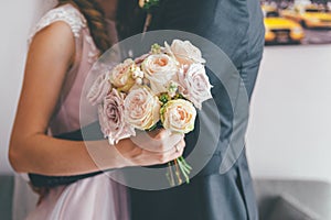 Wedding couple hugging and holding rose bouquet close up