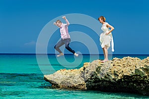 A wedding couple jumping into the ocean