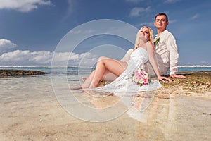 Wedding couple just married lying at water near the beach