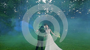Wedding couple kiss and hug color smoke in the park. Slow motion