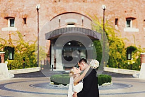 A wedding couple kisses in the front of an entrance to an old ho