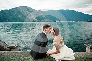 Wedding couple kissing on the background of a lake and mountains