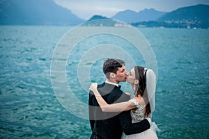 A wedding couple kissing on the background of a lake and mountains