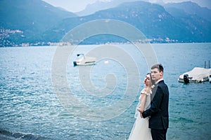 A wedding couple kissing on the background of a lake and mountains