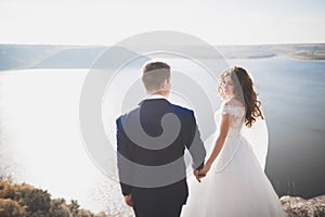 Wedding couple kissing and hugging on rocks near blue sea