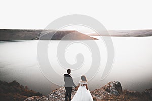 Wedding couple kissing and hugging on rocks near blue sea