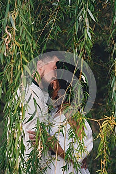 Wedding couple kissing near the willow tree