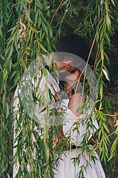 Wedding couple kissing near the willow tree