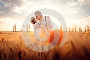 Wedding couple kissing in romantic setting on a wheat field