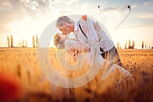 Wedding couple kissing in romantic setting on a wheat field