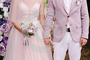 Wedding couple. Lilac, violet, purple, pink marriage concept. Bride and groom holding hands at outdoor wedding ceremony