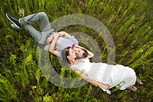 Wedding couple in love lying in green grass in summer meadow