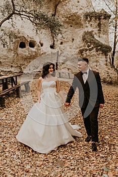 wedding couple in love man and woman walking in autumn forest background of stone rocks