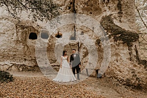 wedding couple in love man and woman walking in autumn forest background of stone rocks