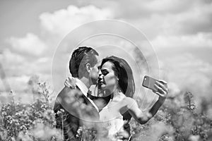 Wedding couple makes selfie. wedding couple kiss in field yellow flowers.