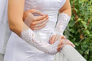 Wedding couple in nature. the hands of the groom embrace the bride. the bride in white gloves