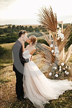 Wedding couple newlyweds kiss after the ceremony at the arch