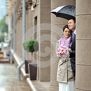 Wedding couple in a rainy day hiding from rain
