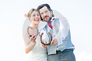 Wedding couple showing horse shoe for luck