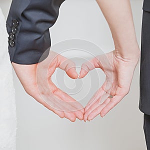 Wedding couple showing shape of heart from their hands.