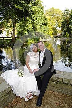 Wedding couple sitting at a smal pond in autumn