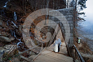 Wedding couple softly kiss on the wooden bridge. Misty day in mountains