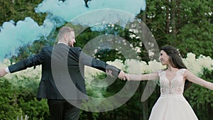 Wedding couple spin together color smoke in the park. Slow motion