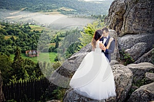 Wedding couple standing in the mountains against the sky. Cute r