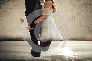 Wedding couple standing on sandy beach and hugging. Bride and groom together. Collage, mirror reflection. Wedding day