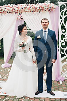 Wedding couple standing under an arch of fresh flowers