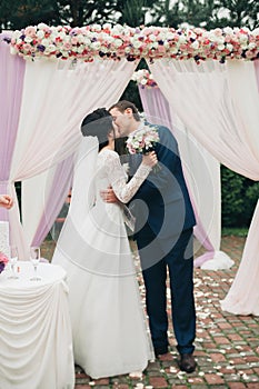 Wedding couple standing under an arch of fresh flowers