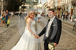 Wedding couple stands on the tramways somewhere in an old part o