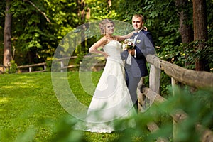 Wedding couple in summer wood near fence