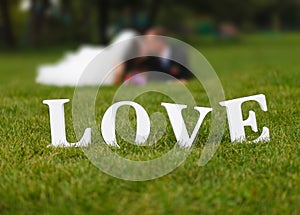 Wedding couple unfocused and love word on the grass