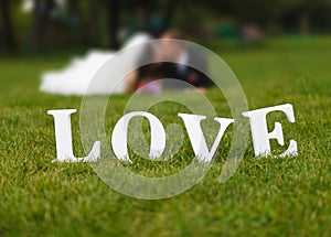 Wedding couple unfocused and love word on the grass photo