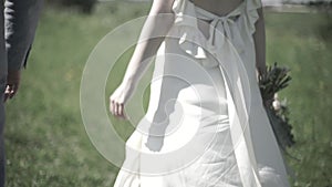 Wedding day. The groom holds the bride's hand, they walk through the woods. Closeup view of married couple holding