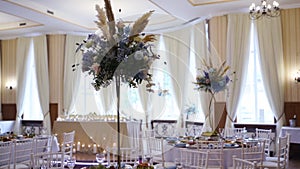 Wedding decor flower bouquets and compositions in restaurant hall with blue, white roses, petals, hydrangea. Holiday