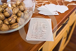 Golden walnut in a glass round vase and a guest seating list. Wedding decor