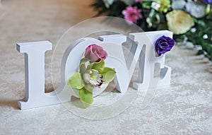 Wedding decor, LOVE letters and flowers on table. Fresh flowers and LOVE decoration on festive table. Luxurious wedding decoration