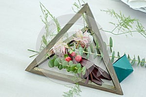 Wedding decor with natural elements. Geometric centerpiece. Flower arrangement consists of eucalyptus, a blushing bride, and other