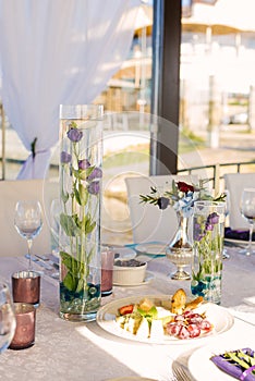 Wedding decor. Purple eustoma flowers are submerged in glass vases flasks