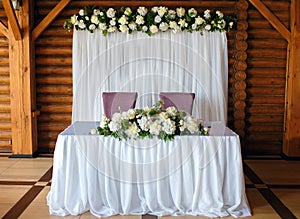 Wedding decor of the restaurant, the table of the newlyweds on a wood background, beautifully decorated decor