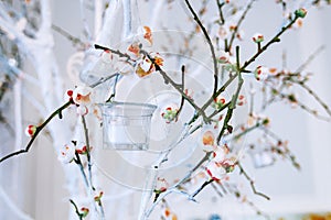 Wedding decor, white and green tree branch with blossoming buds, flowering tree branches with white flowers and a garland of candl