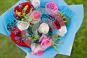 Wedding decorative bouquet of the bride of flowers of red, white and pink roses in blue paper, view from above