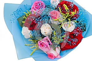 Wedding decorative bouquet of the bride of flowers of red, white and pink roses in blue paper, view from above