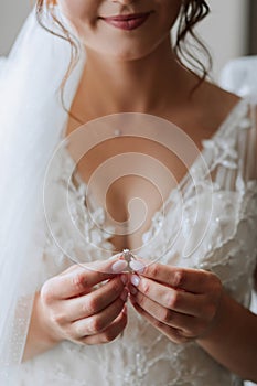 Wedding details. The bride is dressed in a white elegant dress, holding her wedding ring